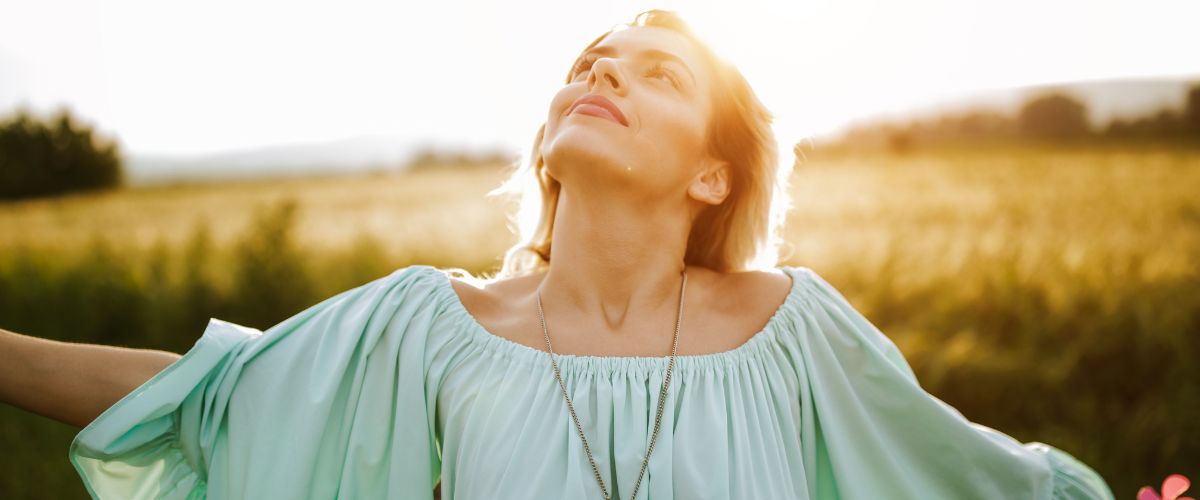 Woman in the sunshine with her arms out symbolising the freedom felt after an energy healing
