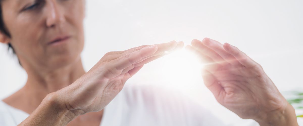 A woman wiht light energy beneath her hands showing energy healing session to restore balance and clarity